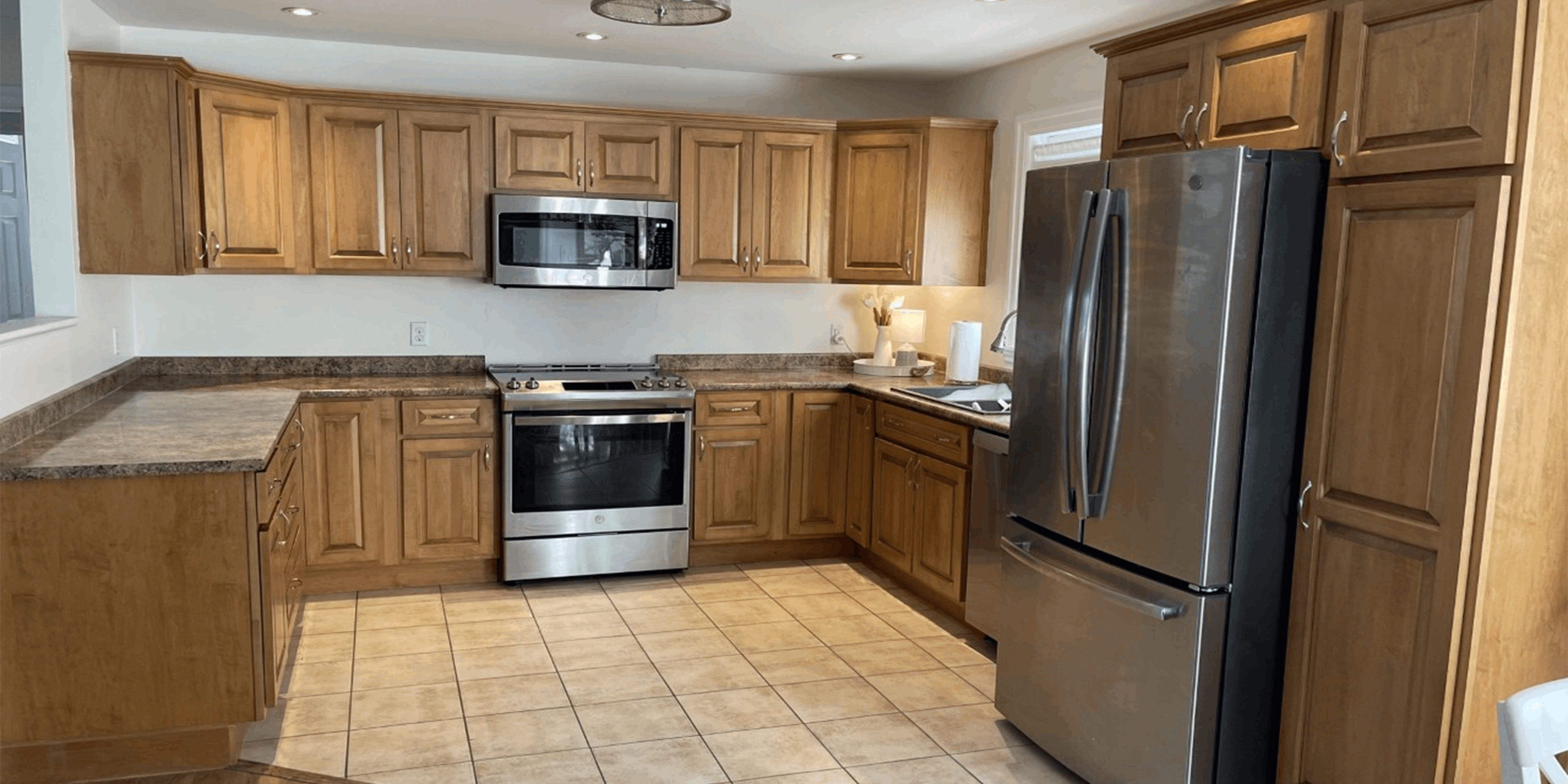 Large kitchen with brown wooden cabinetry and stainless-steel appliances.