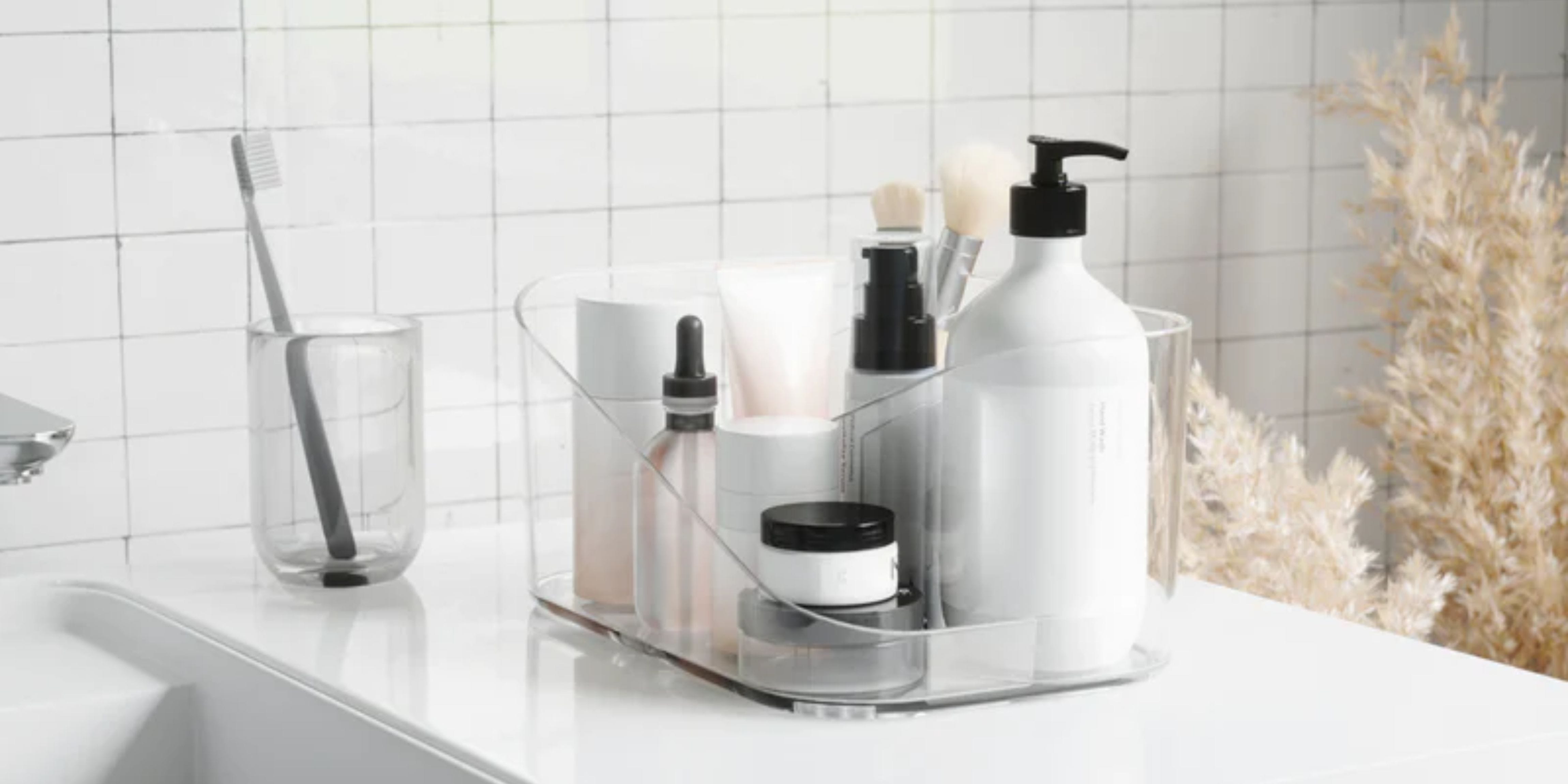 Small bathroom organizer with compartments filled with various bottles, makeup brushes, face masks, etc. On the left, we see a clear glass with a grey toothbrush