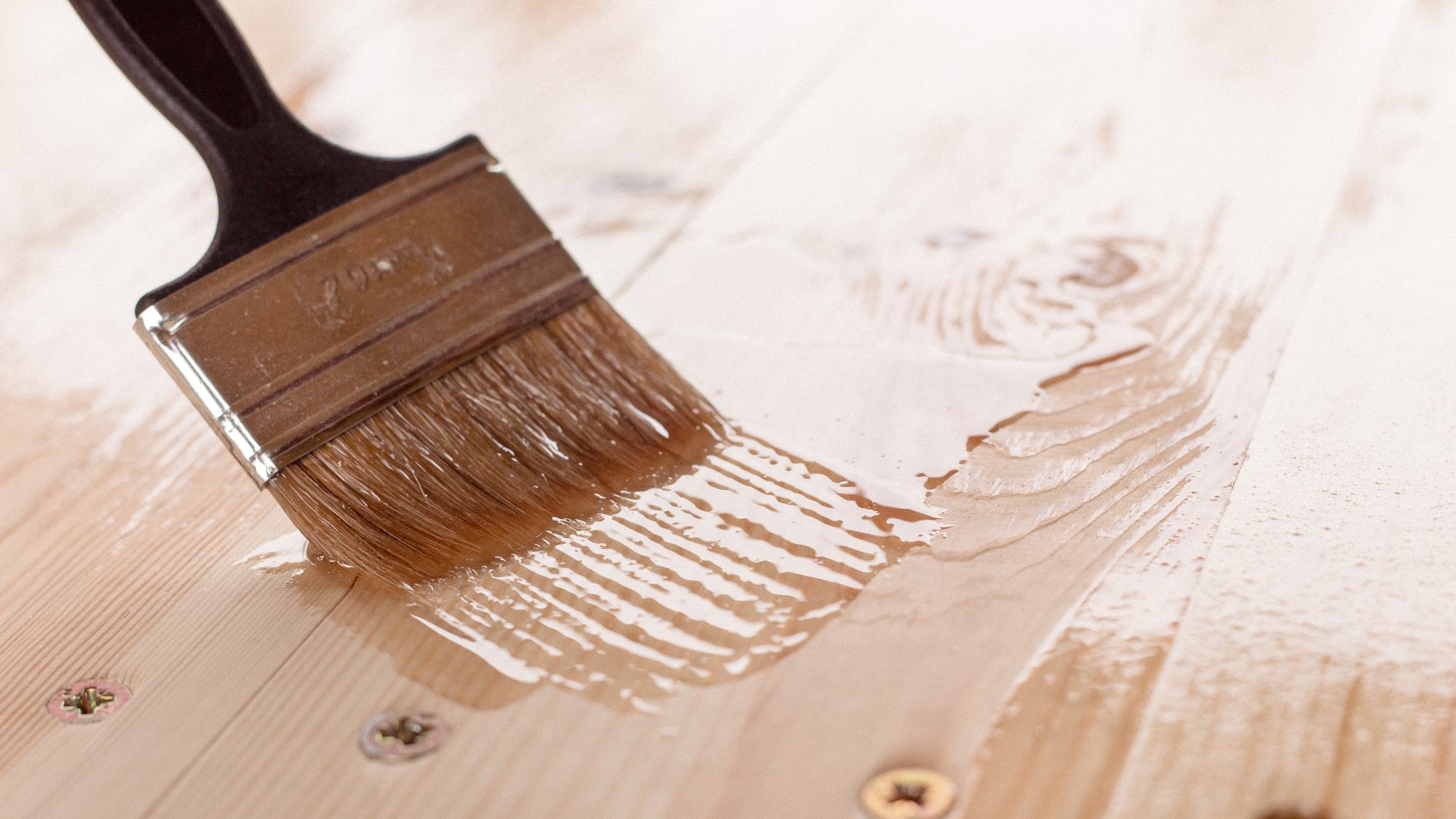 clear stain being applied on wood with brush